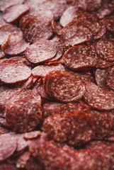 Thinly sliced sausage slices on a black stone board. 