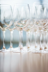 Several rows clear, clean glasses for wine and champagne on counter prepared for drinks.