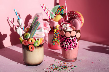 Different delicious freak shakes on color background