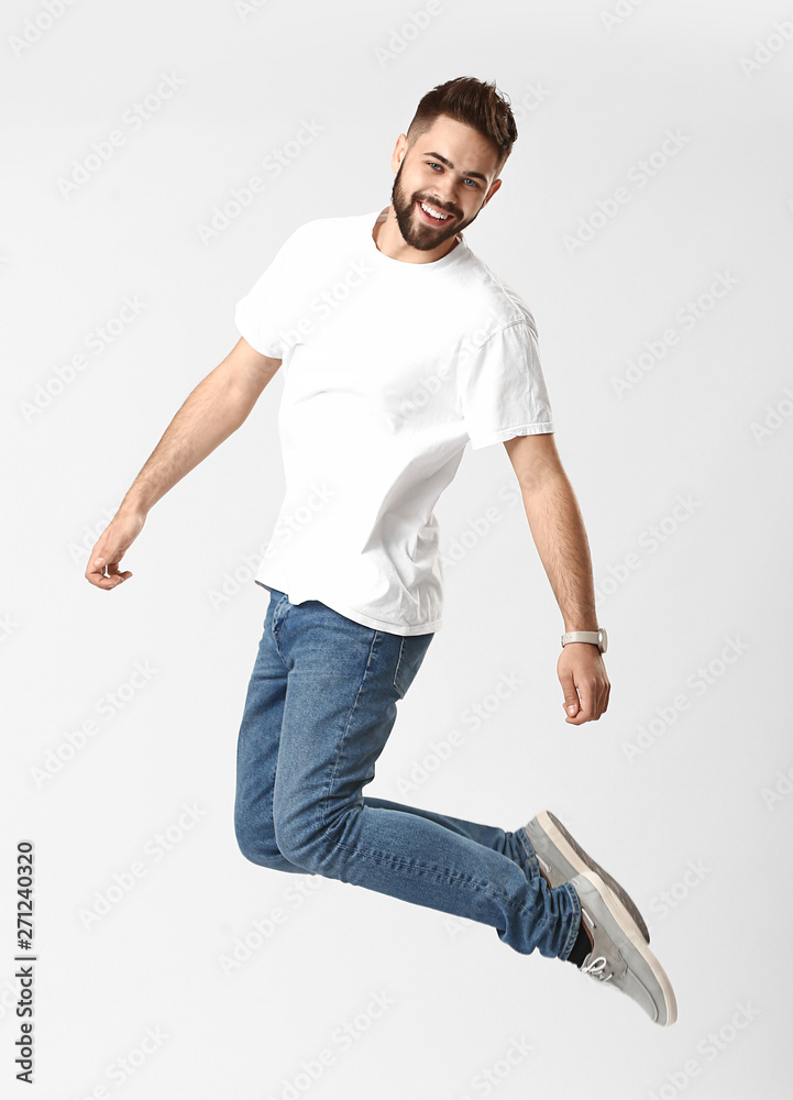 Wall mural Jumping young man in jeans on white background