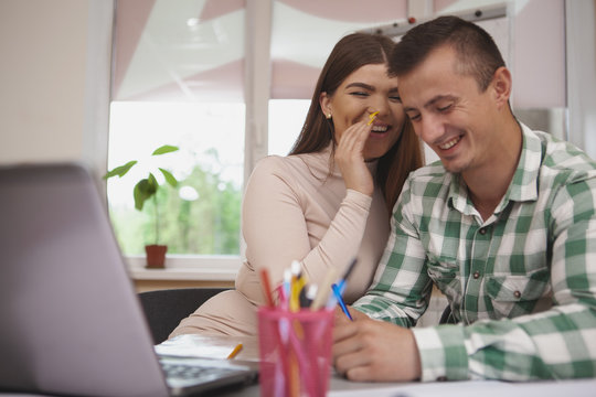 Love, education concept. Charming young couple studying together at college library, using laptop. Beautiful cheerful female student whispering something funny to her boyfriend - Powered by Adobe