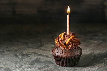Tasty chocolate cupcake candle on grunge background