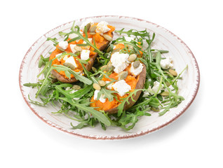 Baked sweet potato with cheese and arugula on white background