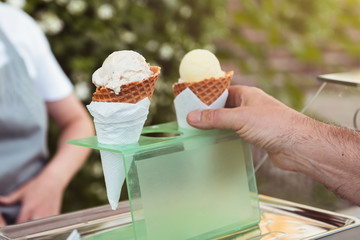 Man's hand taking an ice cream in waffle cone from the plastic holder. Delicious cold dessert.