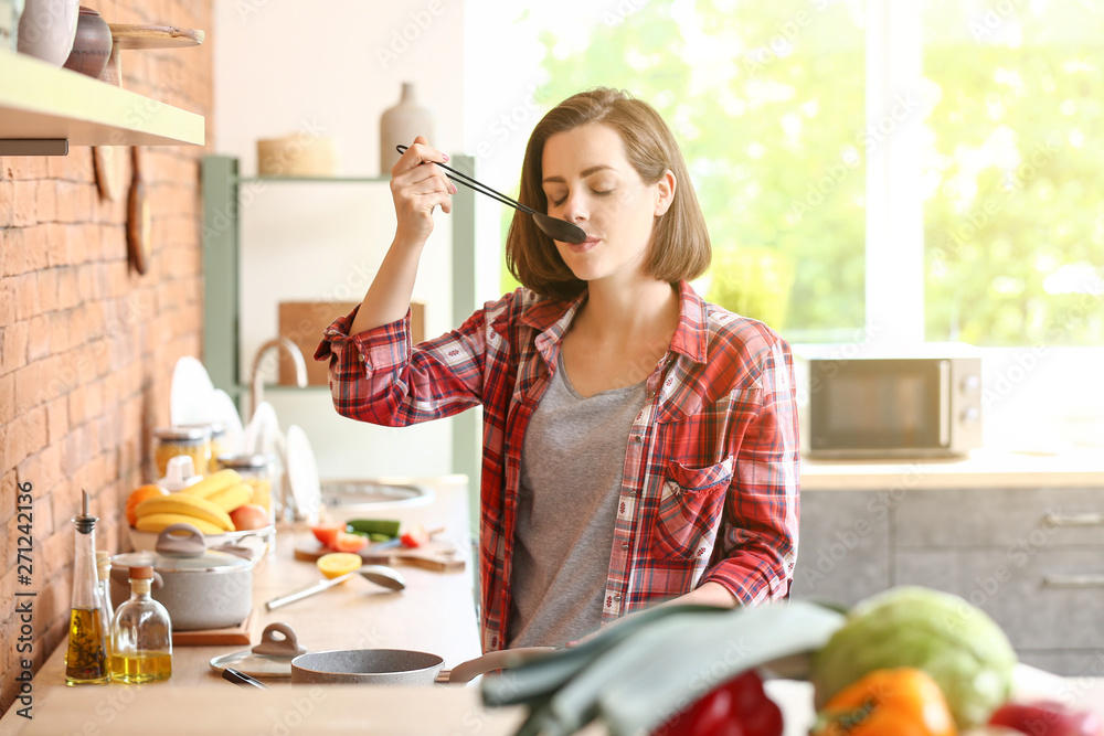 Wall mural Beautiful young woman cooking in kitchen