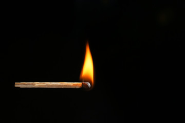 Burning match on dark background