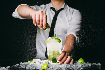 Professional barman squeezing lime making Mojito cocktail