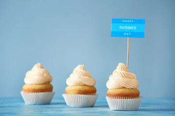 Tasty cupcakes for Father's Day on color background