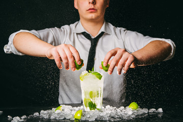 Professional barman squeezing lime making Mojito cocktail