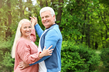 Portrait of happy mature couple dancing in park