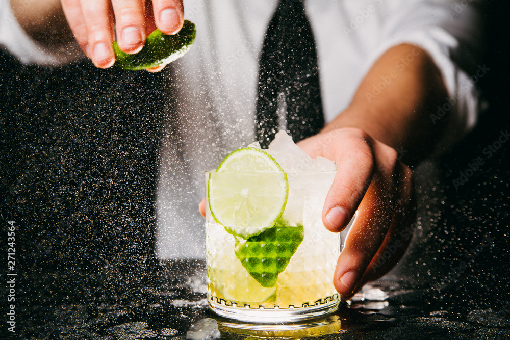 Wall mural close-up of professional bartender squeezing lime making caipirinha cocktail