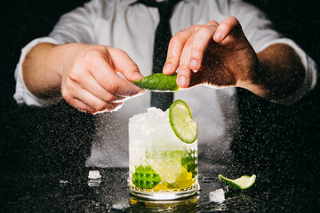 Close-up of bartender squeezing lime making Caipirinha cocktail