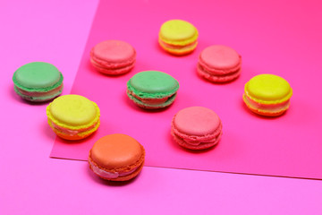 Different color macarons. Red, green, yellow and pink macaroons on purple and pink paper background. 