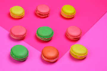 Fototapeta na wymiar Different color macarons. Red, green, yellow and pink macaroons on purple and pink paper background. 