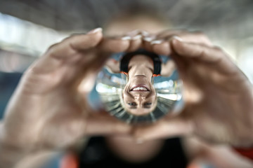 Fototapeta premium Reflection of sportive woman in glass ball in her hands