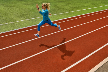 Sportive blonde woman training at open stadium
