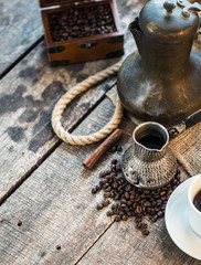 coffee cup, metal turk and coffee beans on a wooden background