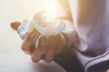 female hands wresting white sheet of paper and making paper ball