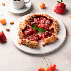 homemade strawberry galleta (biscuit) on a white plate on a light marble backdrop, strawberries and cherries as part of composition