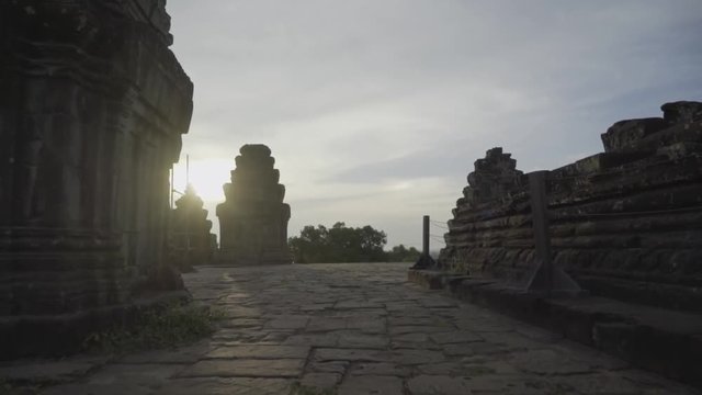 Walking on the top of a Khmer temple in Cambodia; setting sun revealed from behind top of temple.