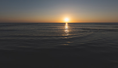 sunset over the horizon of the ocean with cloudless sky