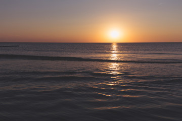 sunset over the horizon of the ocean with cloudless sky