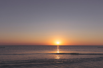 sunset over the horizon of the ocean with cloudless sky