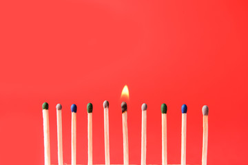 One burning match among non-burning ones on color background. Concept of uniqueness