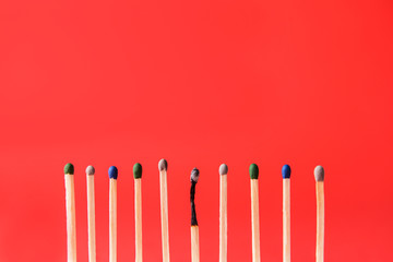 One burnt-out match among unburnt ones on color background. Concept of uniqueness