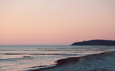 sunset over the beach with rows of groins in the sea