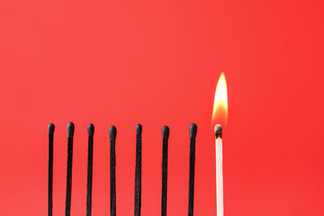 One burning match among burnt-out ones on color background. Concept of uniqueness