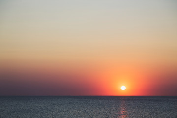 sunset over the horizon of the ocean with cloudless sky