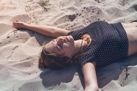young woman laying on the beach with closed eyes