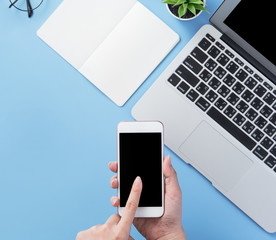 Woman holding smartphone with a minimal blue desk, concept of online shopping, internet payment, e-commerce, copy space, flat lay, top view, mock up