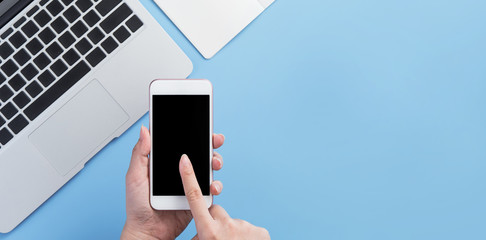 Woman holding smartphone with a minimal blue desk, concept of online shopping, internet payment, e-commerce, copy space, flat lay, top view, mock up