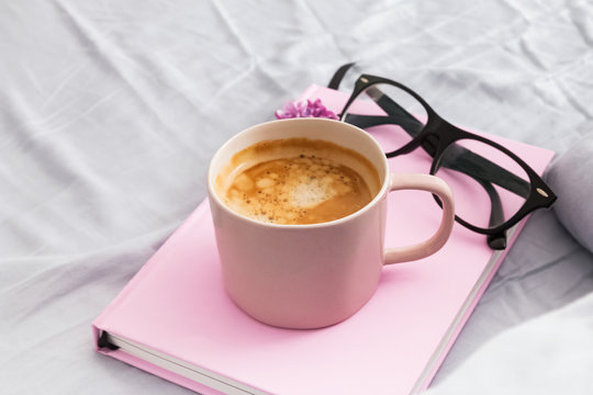 Morning composition with coffee, pink notepad or diary and glasses