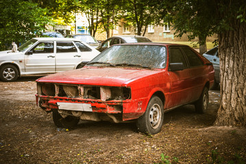 Damaged old production car in the city yard - retro style photo