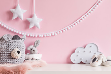 Cozy scandinavian newborn baby room with gray basket ,white stars lamp, cloud, plush rabbit and children accessories. Stylish interior with pink walls and haniging white garland.Template. Copy space. 