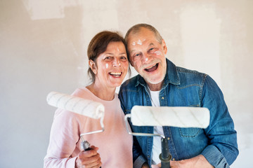Senior couple painting walls in new home, having fun. Relocation concept.