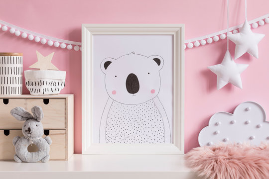 Modern scandinavian newborn baby room with mock up poster frame, plush rabbit, wooden box, cloud and children accessories. Cozy interior with pink walls. Haniging cotton garland and stars. Template