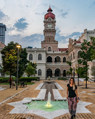 young girl standing in front of classic building and fountain