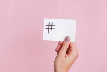 Woman's hand holding a paper card with hashtag symbol drawn on it