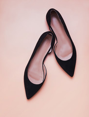 Feminine black suede shoese isolated on peach color background