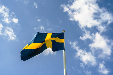Flag of Sweden swedish national blue and yellow flag in the wind over blue coludy sky