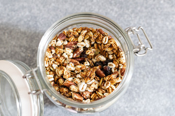 Homemade granola with pecan nuts in glass jar, selective focus, gray background