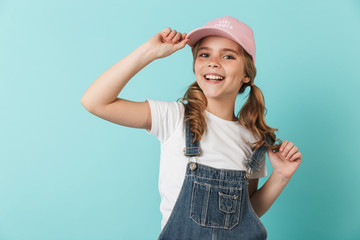 Pretty happy young little girl posing isolated over blue wall background.