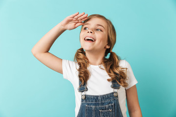 Happy young little girl posing isolated over blue wall background.