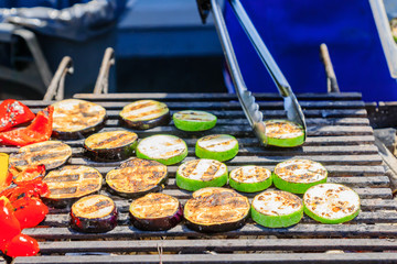 the chef cooks vegetables on grill. Slices of zuccini, eggplant, pepper roasted on open fire