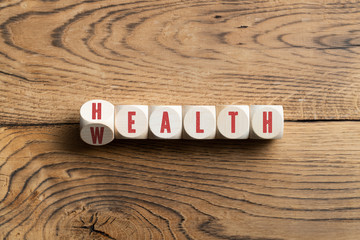 cubes showing the word "health" and "wealth" at the same time, symbolizing to keep the balance