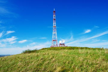 Repeater. Tower of digital television on a hill against the blue sky.